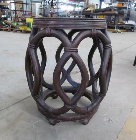 Dark brown wooden garden stool with intricate woven design, indoors on concrete floor.