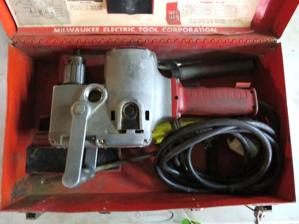 Milwaukee electric tool in a red metal case. Gray tool with red handle and black cord.
