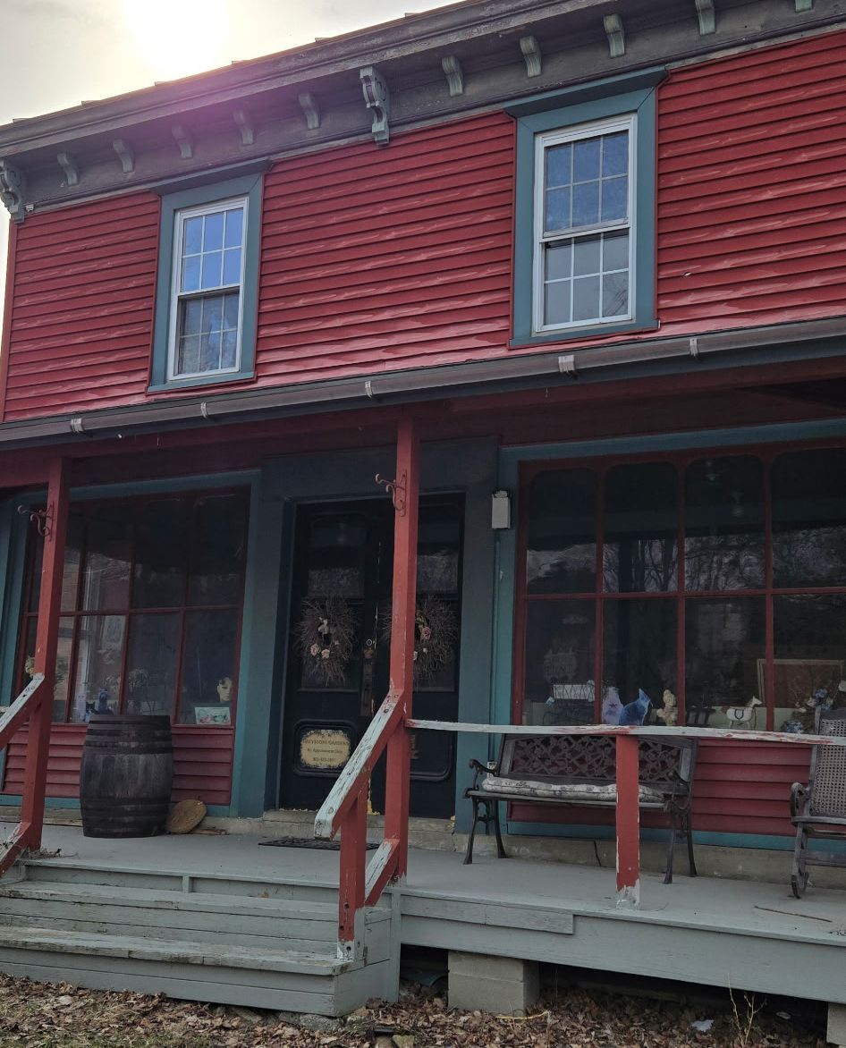 A two-story building with red horizontal siding, a covered porch, and large windows.