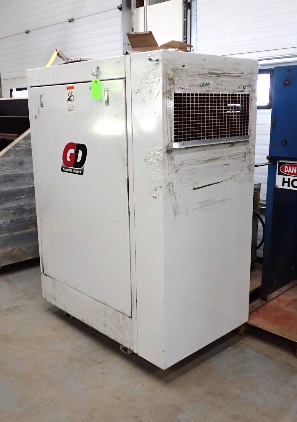 Large, white industrial cabinet with a metal grill, logo on the door, and wheels. In a garage-like setting.