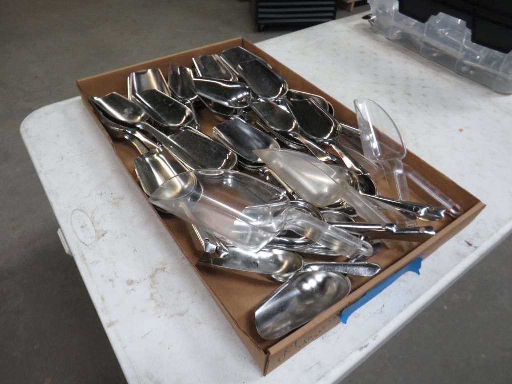 A cardboard box filled with silver and clear scoops on a white table.
