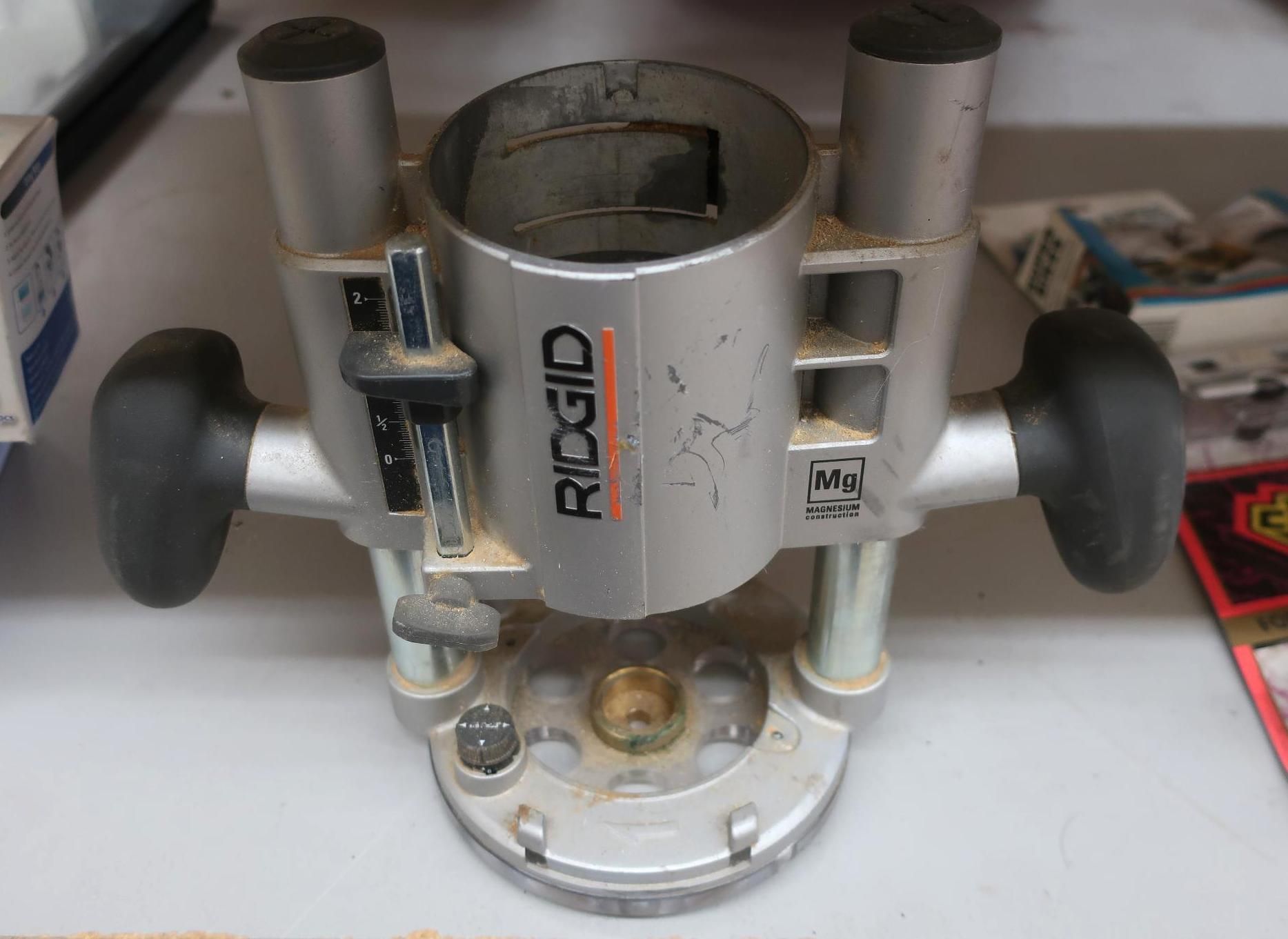 Silver and black Ridgid router base on a white surface.