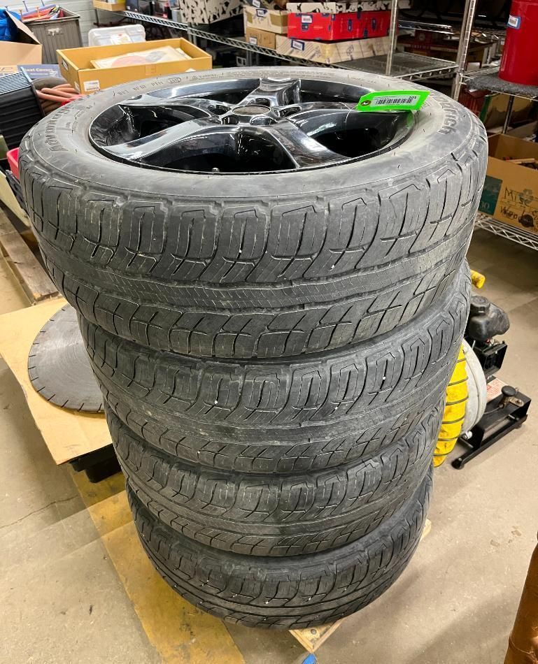 Four black tires stacked on a pallet, with a black wheel on top.