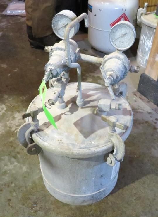 Silver industrial pressure pot with gauges and valves.