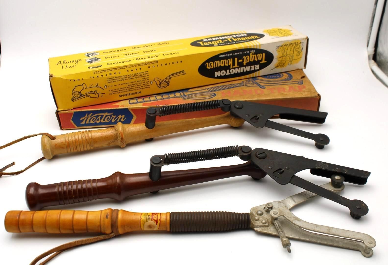Assorted fishing rod holders and tools with two cardboard boxes on a white surface