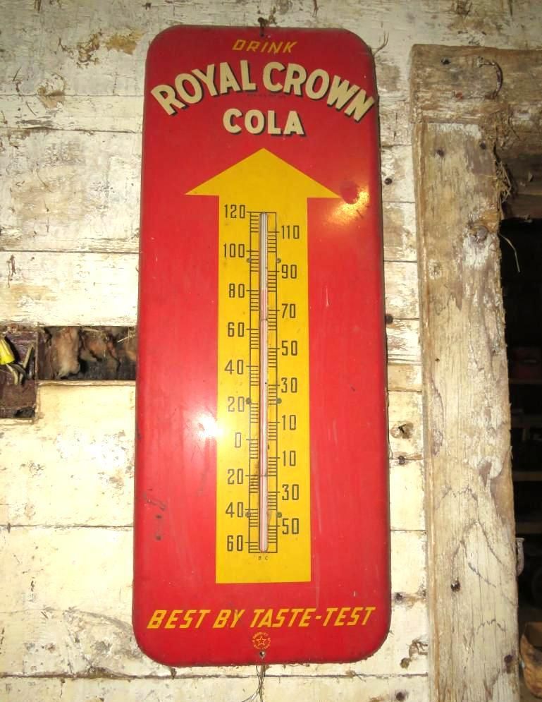 Red Royal Crown Cola thermometer sign on a wall, with temperature scale.