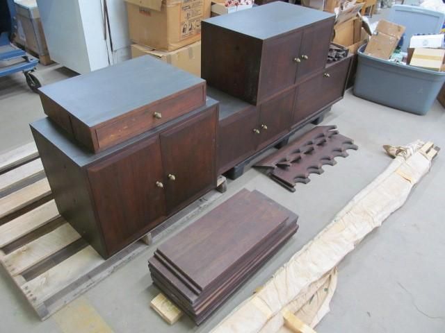 Dark wood furniture pieces in pieces on a pallet, ready for assembly.