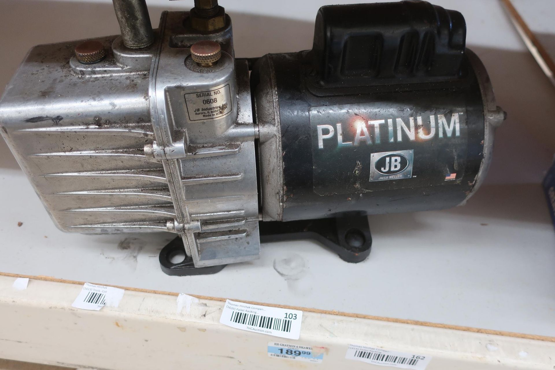 Platinum JB vacuum pump, silver and black, on a shelf.