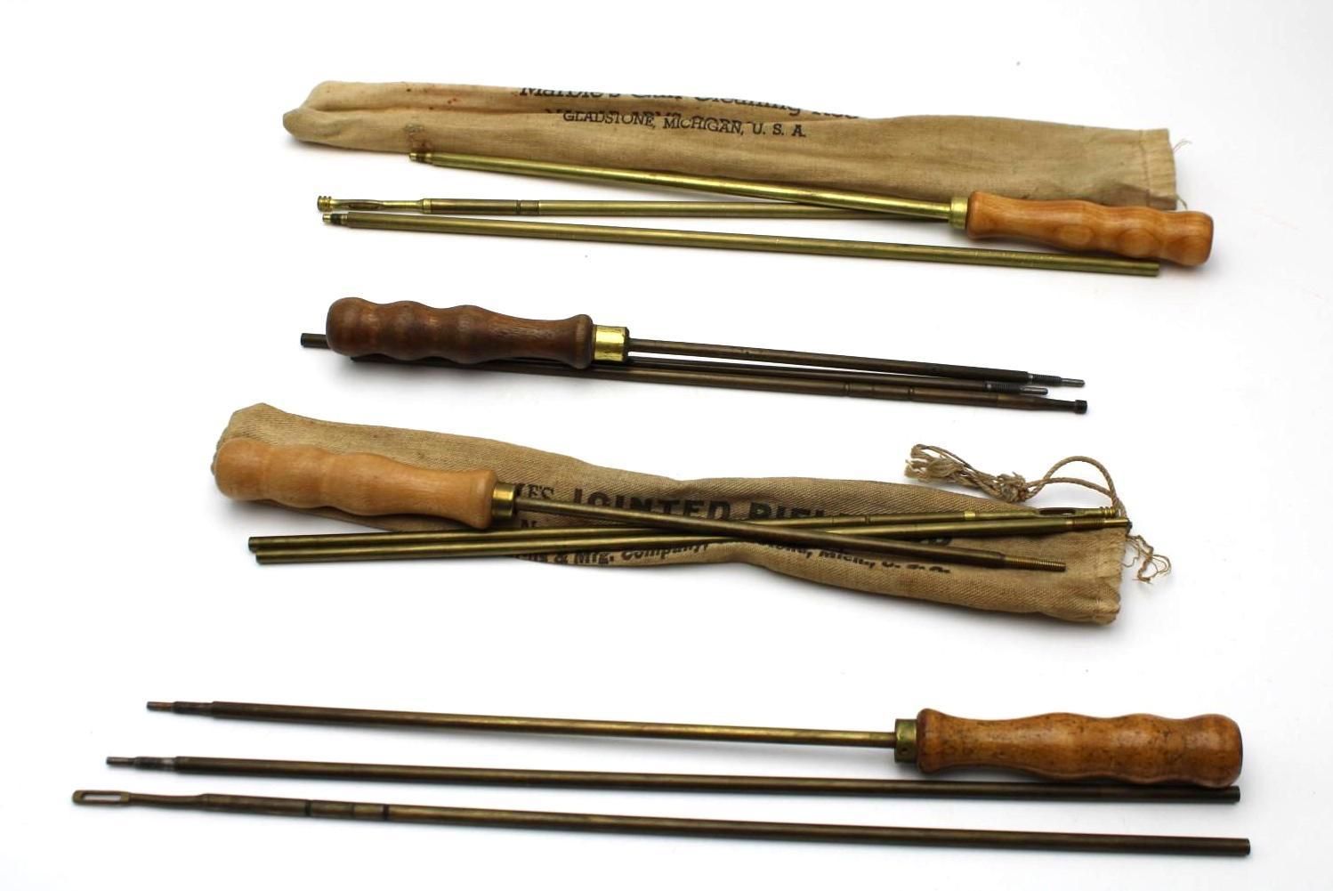 Three old wooden-handled tools with long metal tines, arranged horizontally on a white background