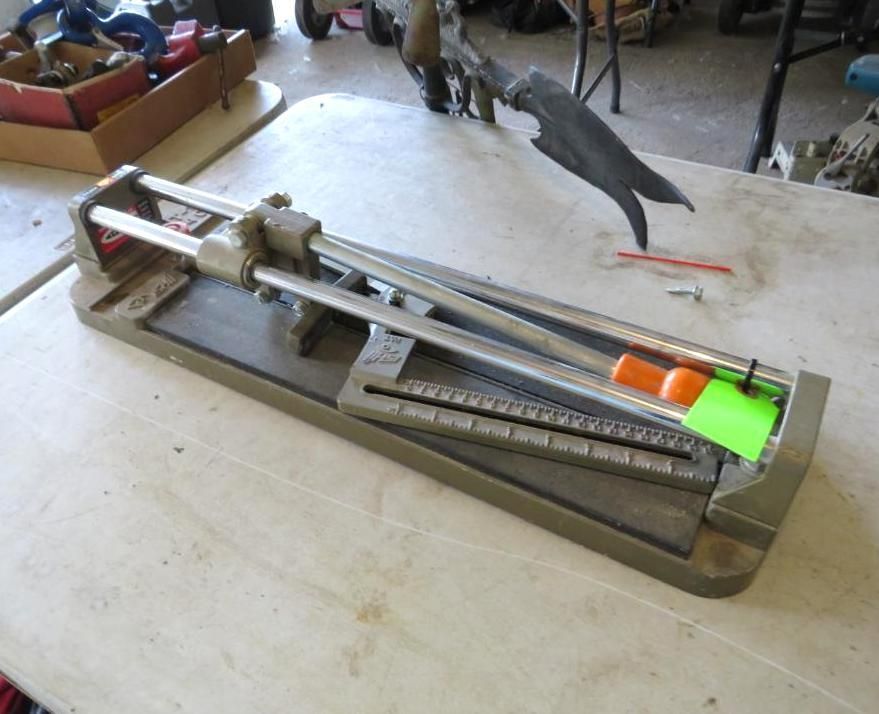 Tile cutter on a table with a scale and orange and green markers.