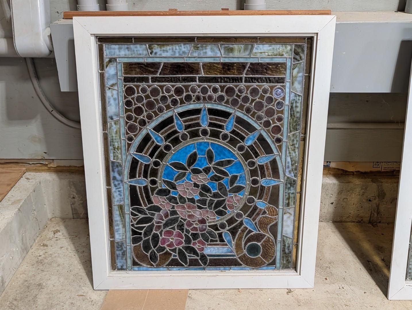 Decorative stained-glass panel in a white frame with blue and pink floral mosaic pattern