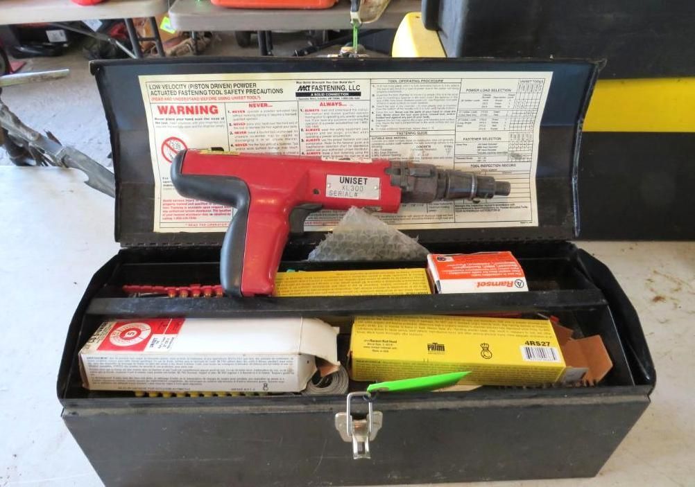 Black toolbox open, containing a red power tool and various supplies; instruction sheet visible in the lid.