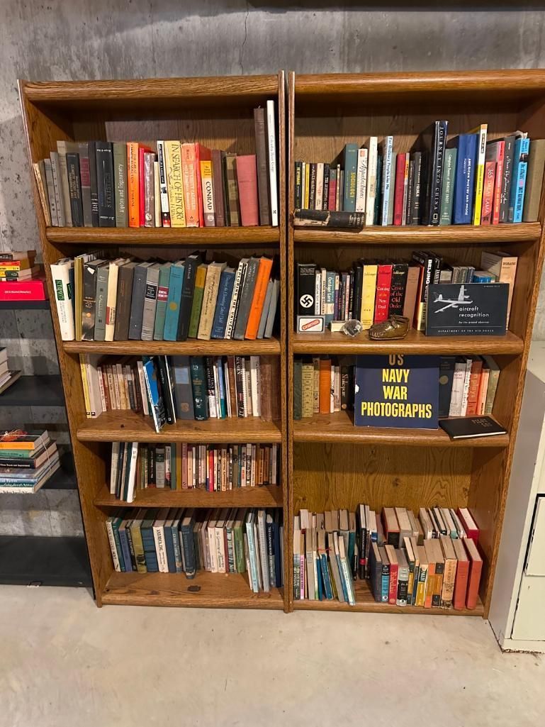 Two wooden bookshelves filled with books in a room with a concrete floor.