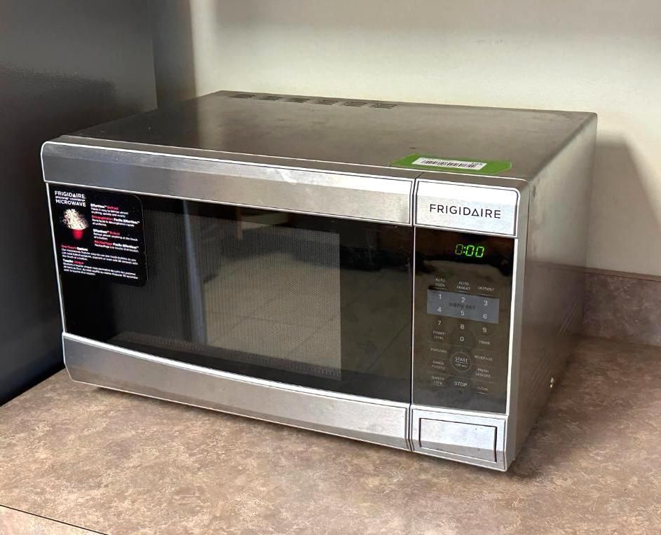 A Frigidaire microwave oven is on a countertop. It's stainless steel with a digital clock and control panel.