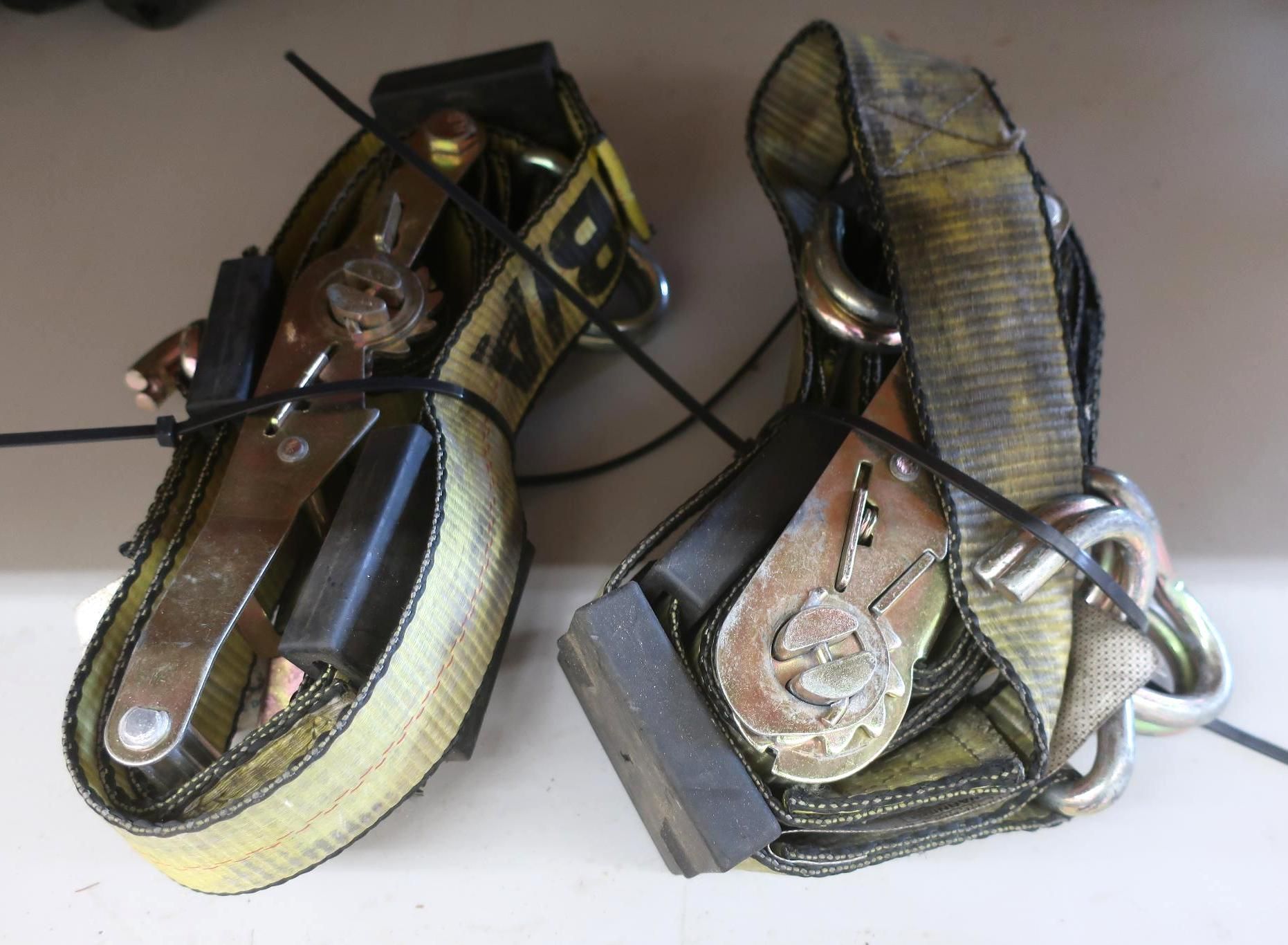 Two yellow ratchet straps with metal hooks and black rubber blocks.