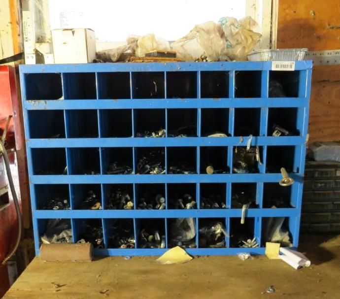 Blue parts organizer with various items in its compartments, placed on a wooden surface.