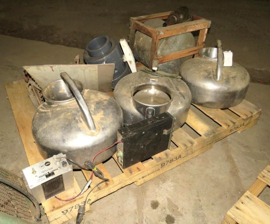 A wooden pallet holds several metal containers, along with electrical components.