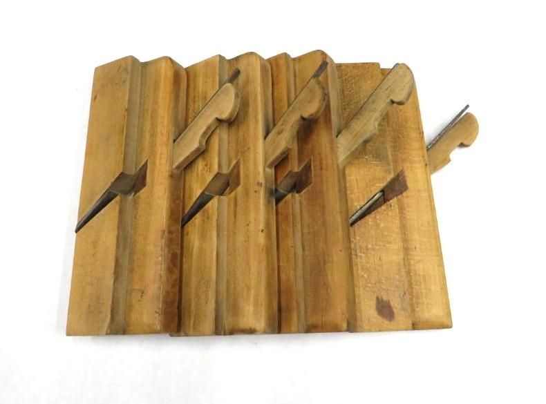 Wooden molding planes arranged in a row. Each has a blade, with a stepped design. Brown.