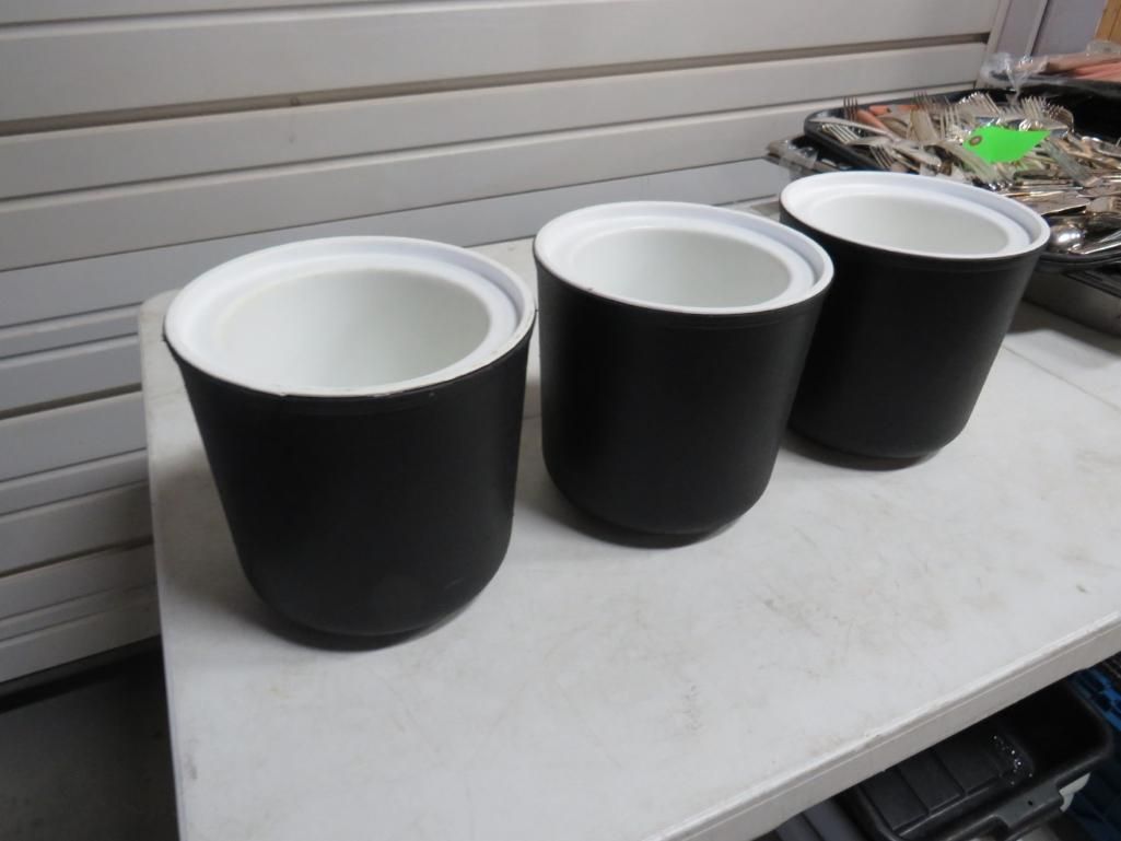 Three black cylindrical containers with white rims on a white surface.