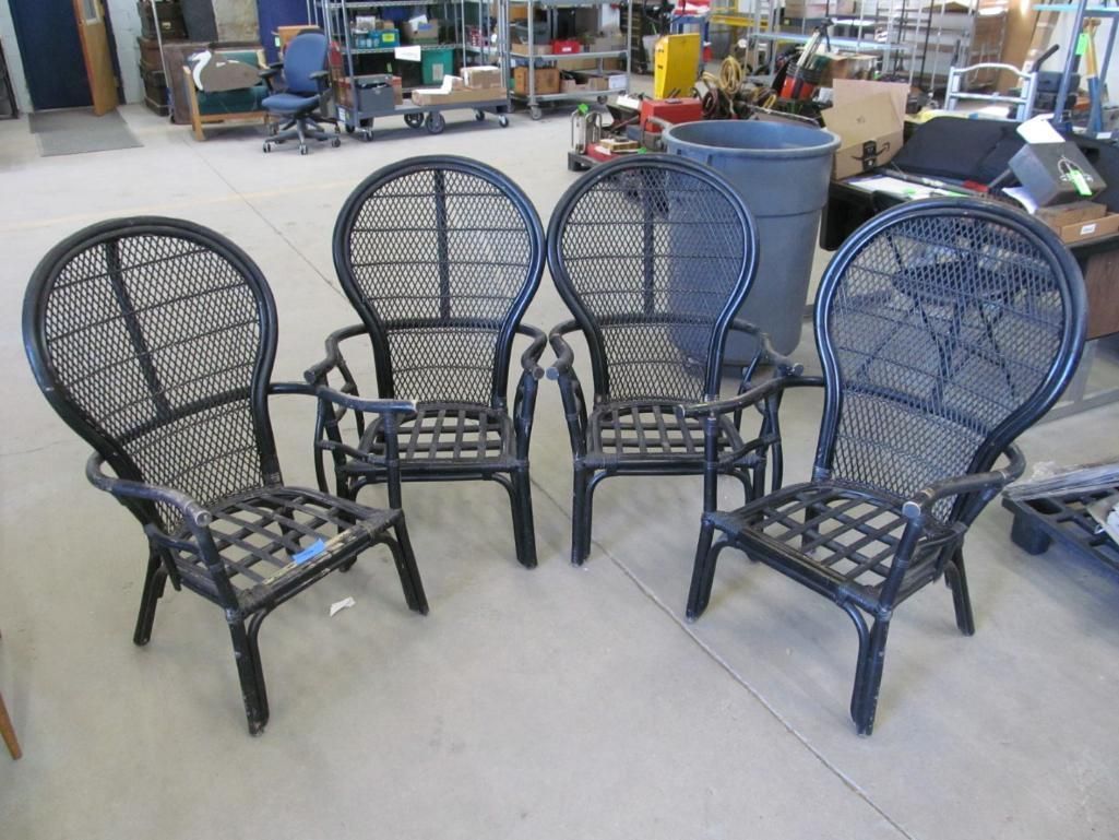 Four black wicker chairs arranged in a room.