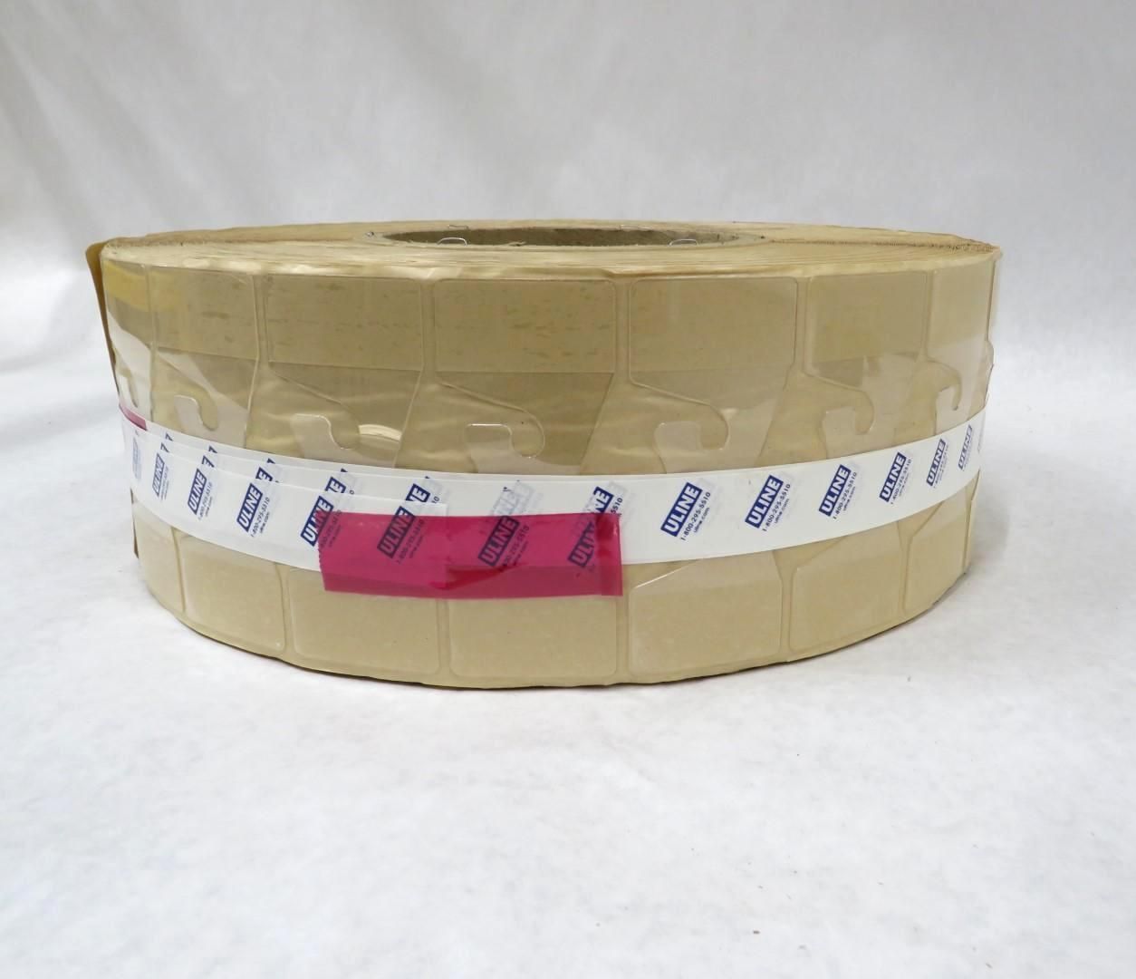 Tan roll of adhesive labels with a white and blue band and a pink label patch.