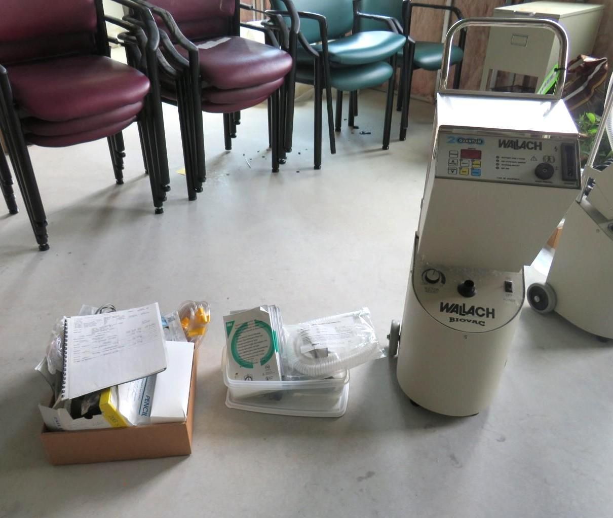 Medical equipment and supplies on a floor next to a stack of chairs.