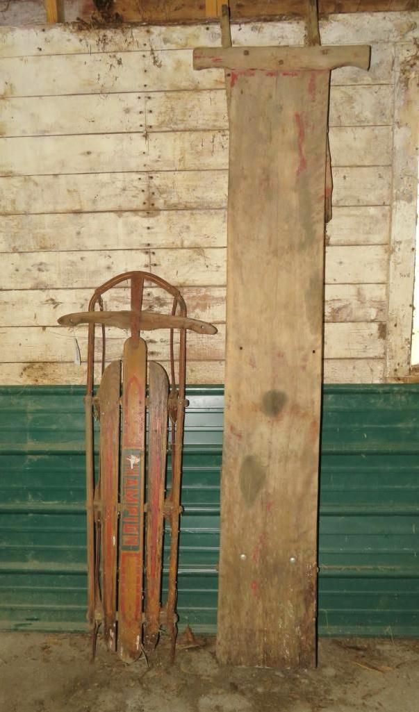 Vintage sled and long wooden plank leaning against a wall. Brown, green, and white.
