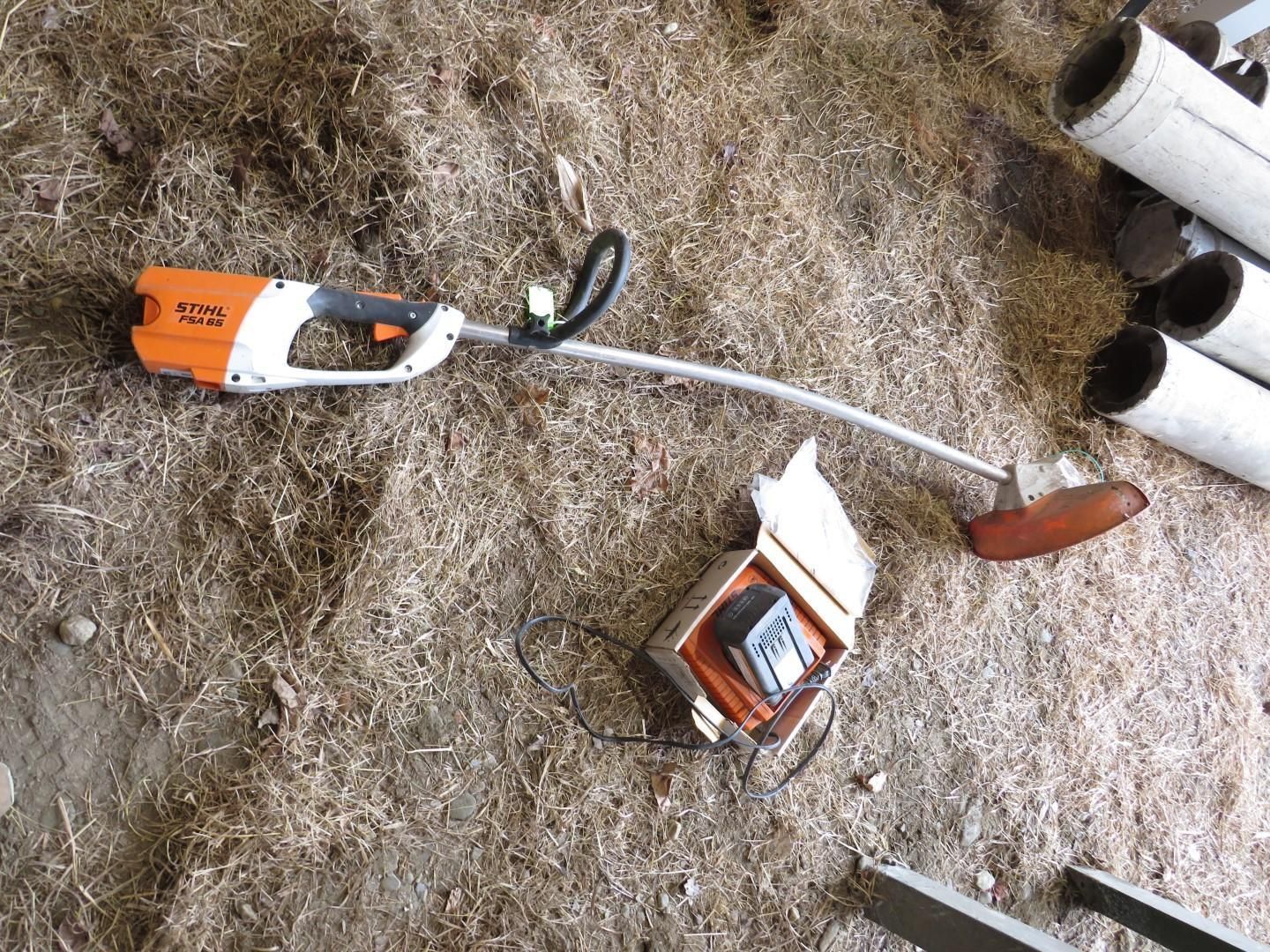 Cordless weed whacker, detached battery pack on ground.