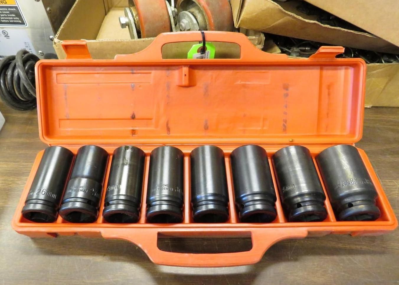 Open orange toolbox containing seven dark, cylindrical impact sockets.