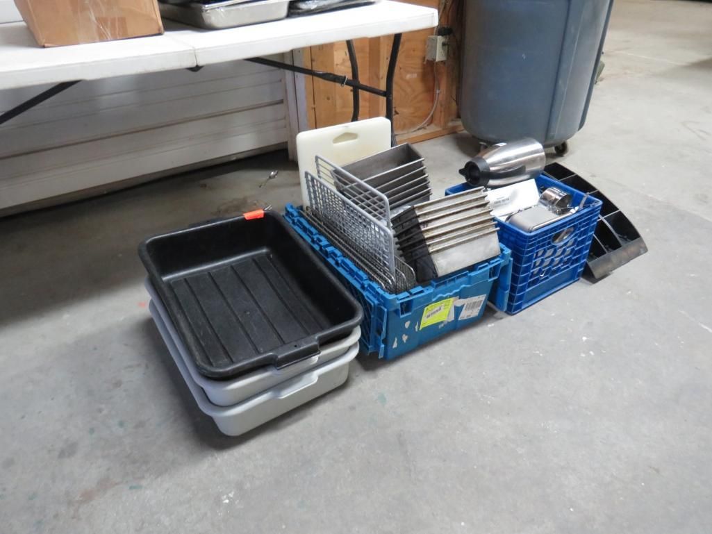 Assorted containers, including bins and trays, are on a concrete floor near a table.