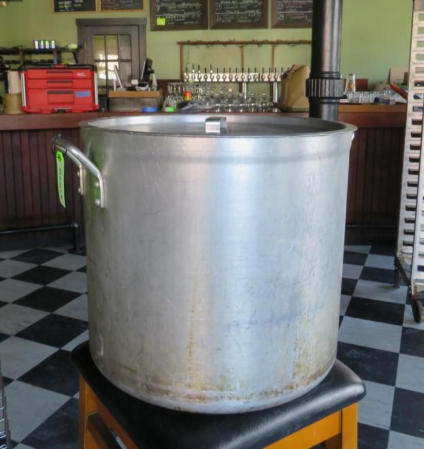 Large metal pot on a stool inside a bar with a checkered floor.