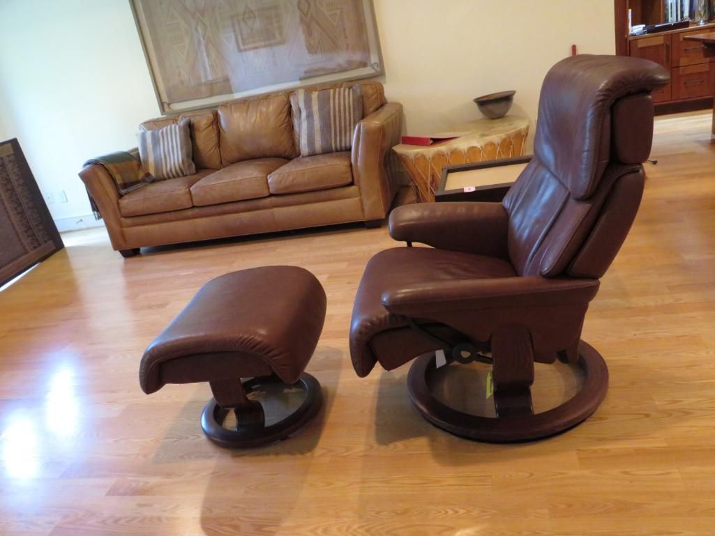 Brown leather recliner chair with matching ottoman on a wood floor.