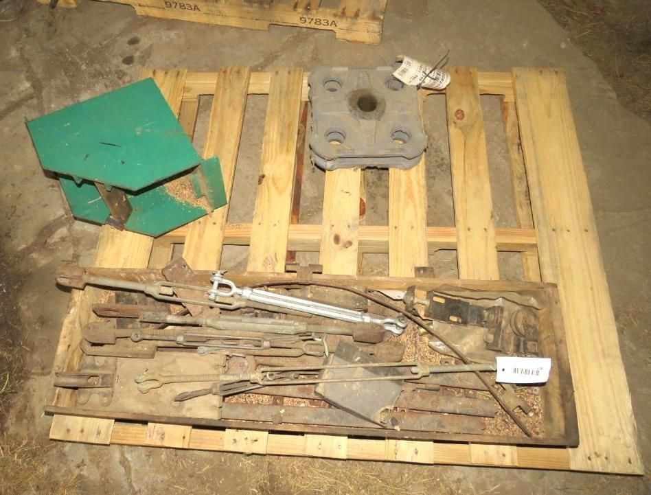 Wooden pallet holding metal industrial parts, including a green box and a large square piece.