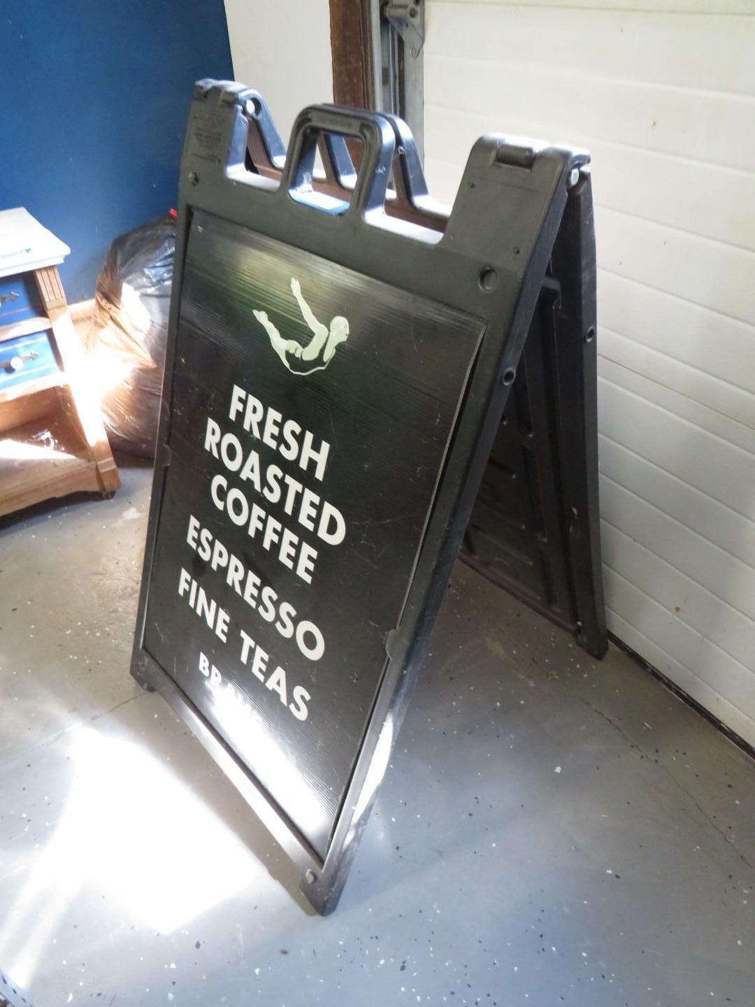 Black A-frame sign with white text, advertising fresh roasted coffee, espresso, and fine teas.