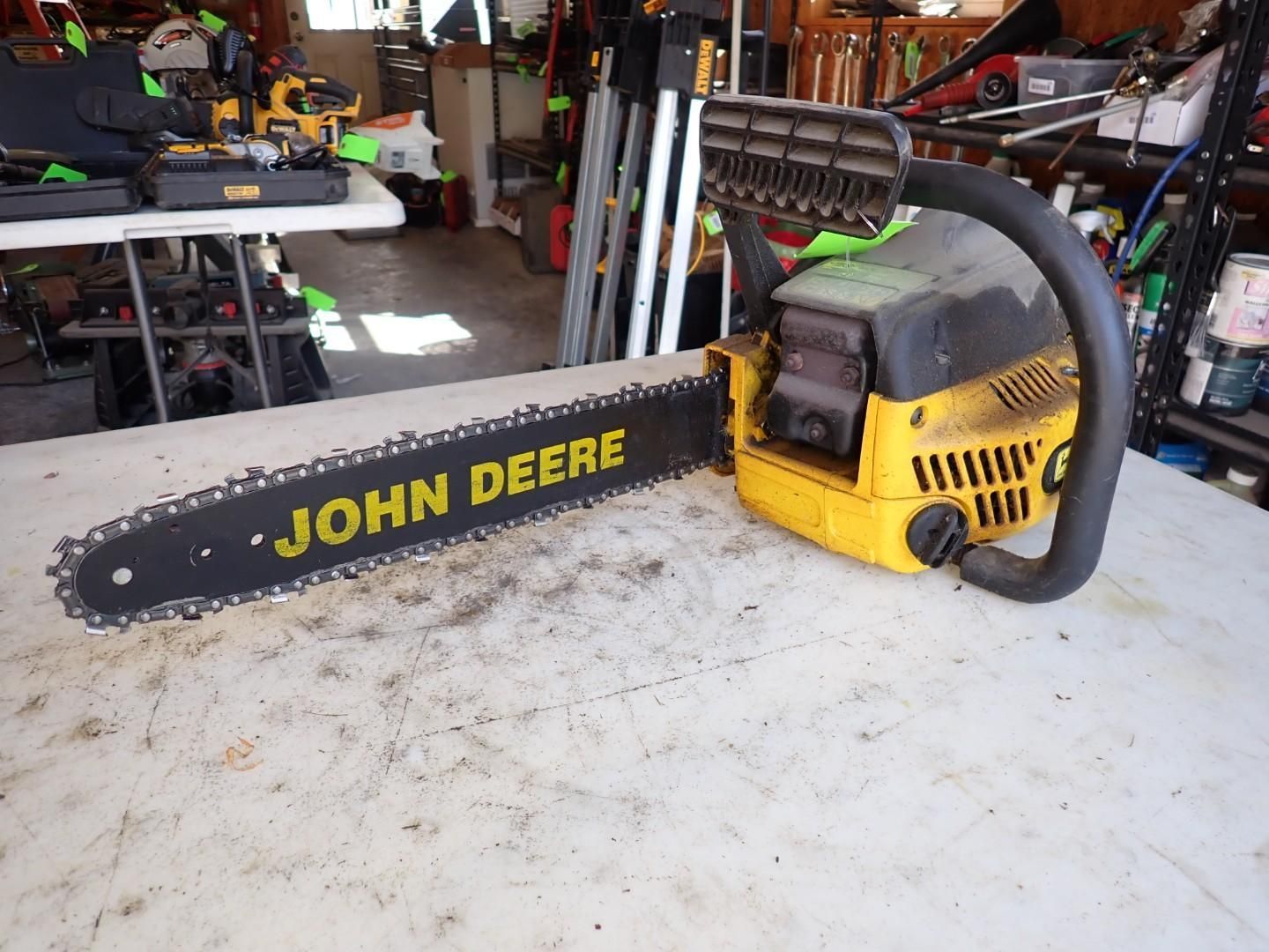 Yellow and black John Deere chainsaw on a workbench in a garage workshop