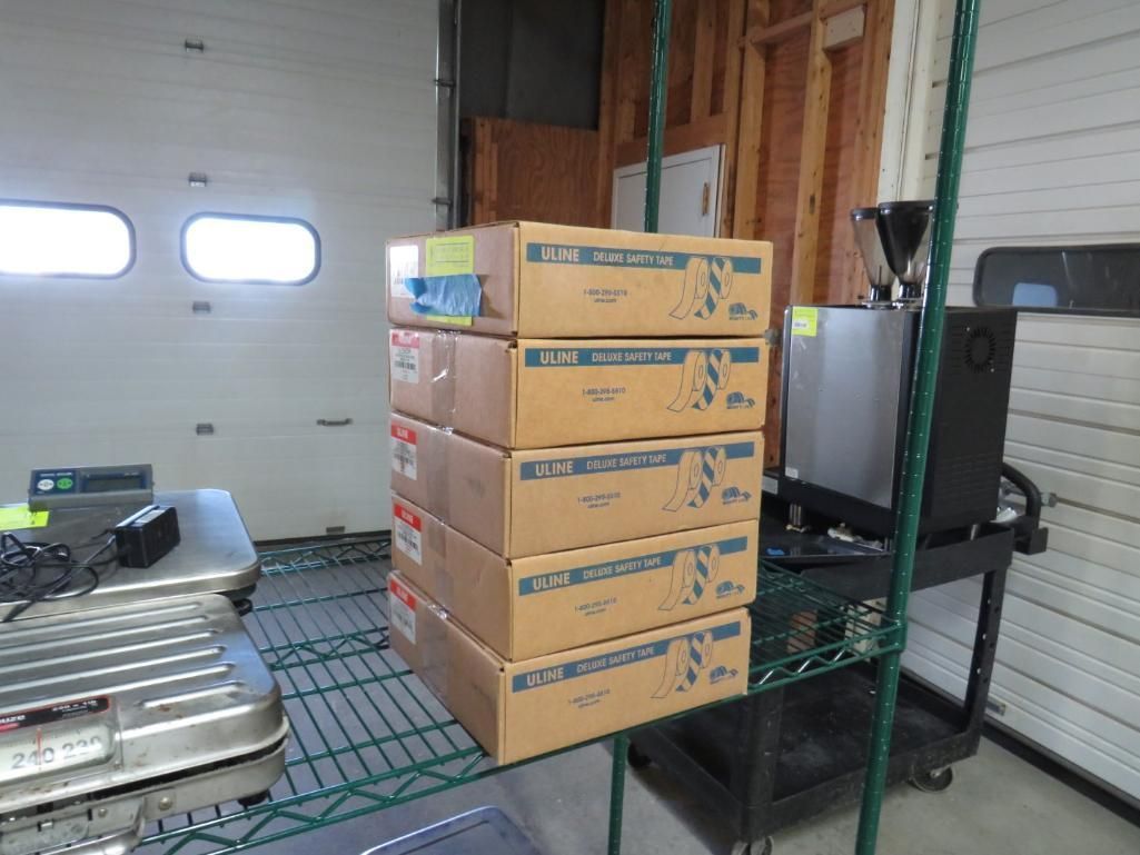 Boxes stacked on a wire shelf inside a room with a garage door.