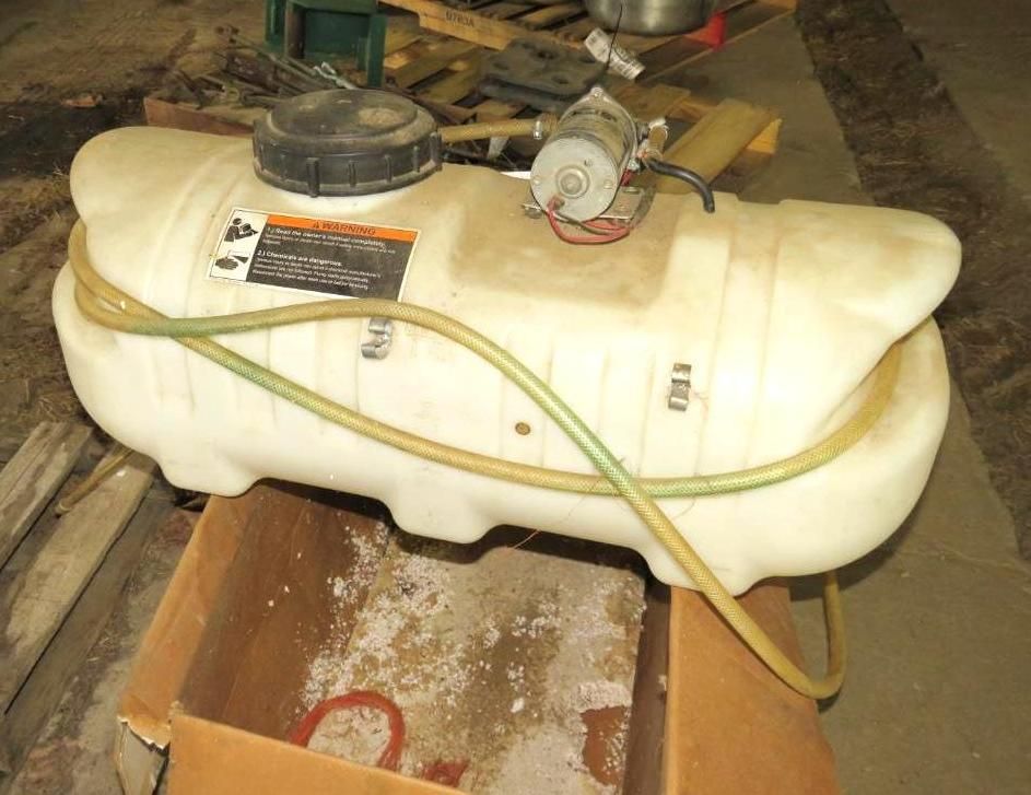 White plastic sprayer tank with motor, hoses, and cap, sitting in a cardboard box.