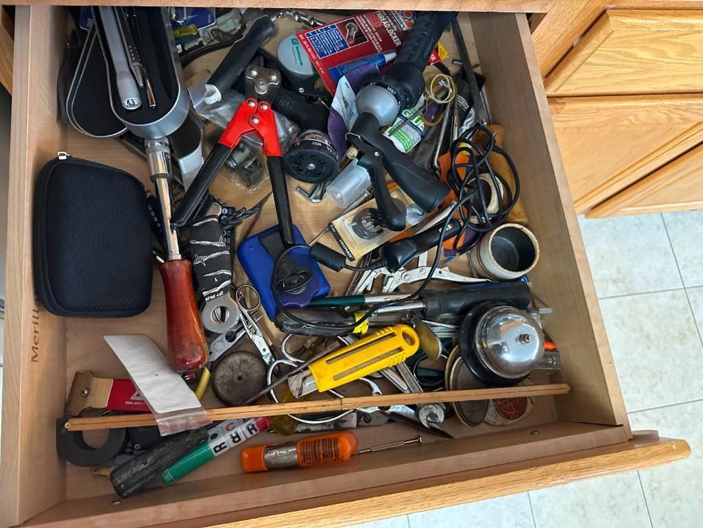 Drawer filled with various tools and objects, including a screwdriver, keys, and a tape measure.