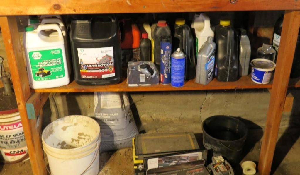 A wooden workbench with various oil containers and auto parts stored on shelves in a garage.