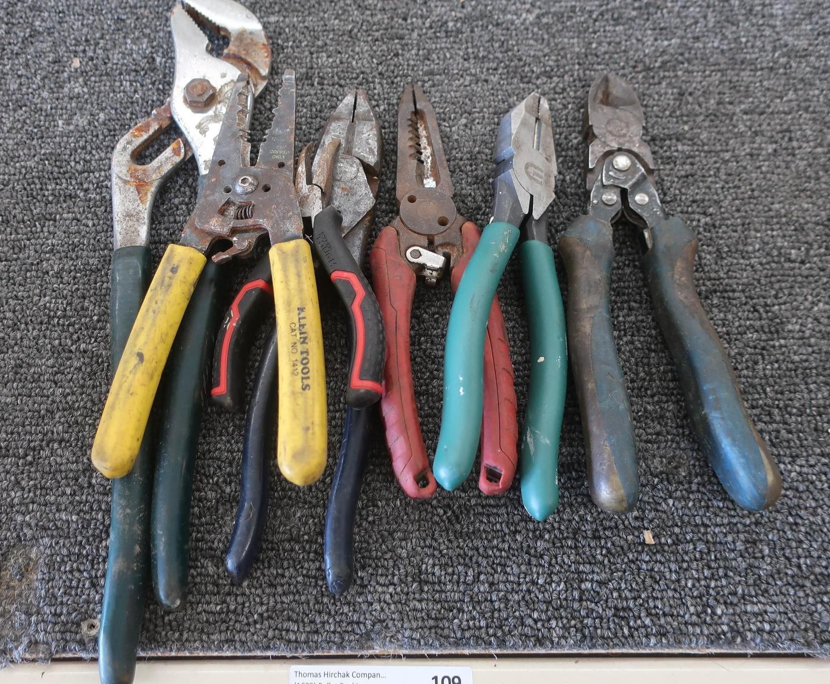 Assorted pliers of various sizes and colors, arranged on a textured surface.