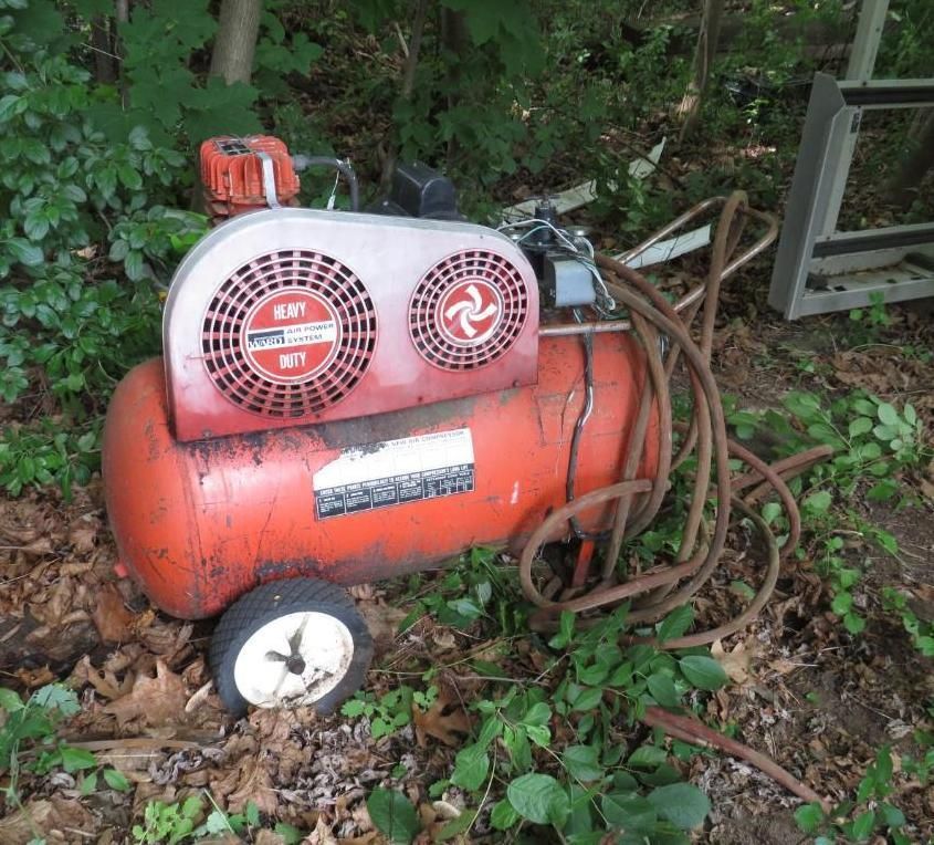 Orange and white industrial air compressor with wheels.