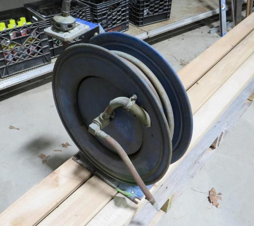 Blue hose reel with a coiled hose on wooden beams.