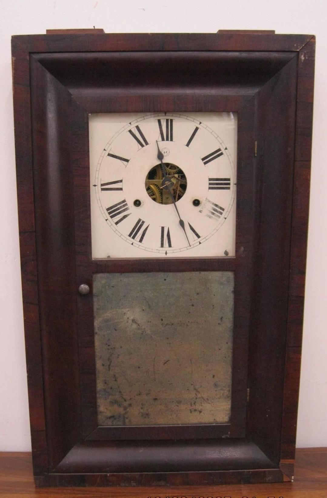 Antique wooden clock with a visible clock face and a mirror below.