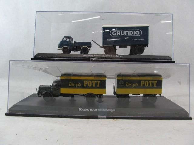 Two model trucks in display cases; one Grundig, one Pott, both on black bases.