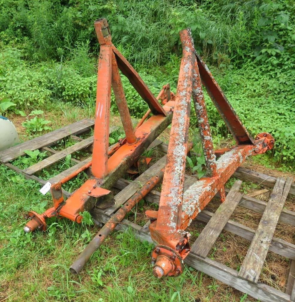 Two orange tractor trailer axles on wooden pallets.