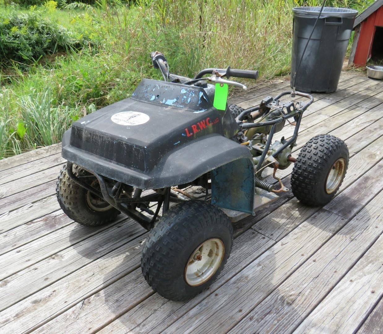 A small, partially disassembled ATV with black and blue body on a wooden deck.