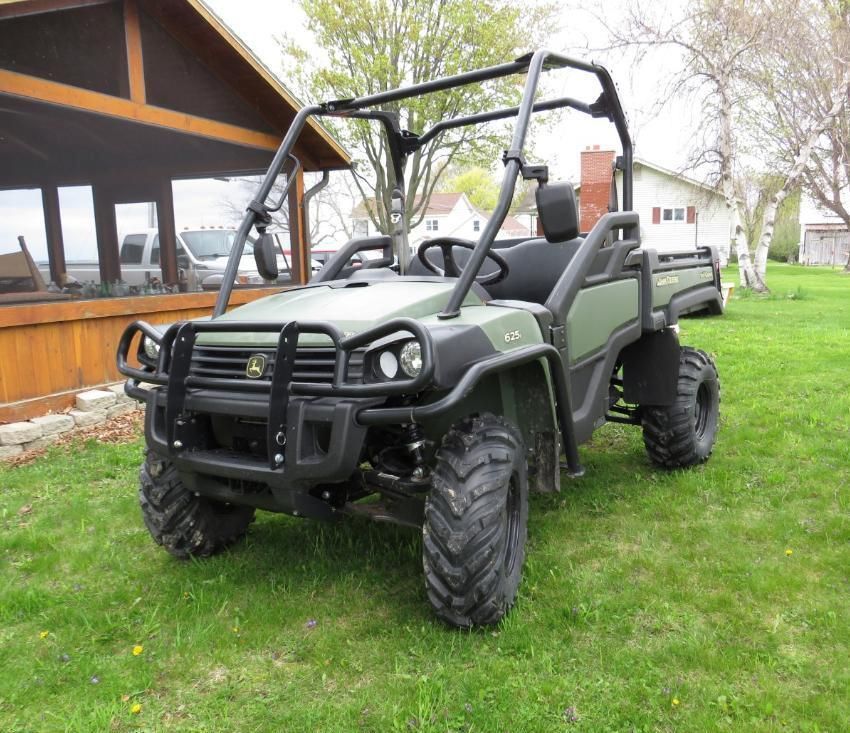 Green John Deere utility vehicle parked on grass.