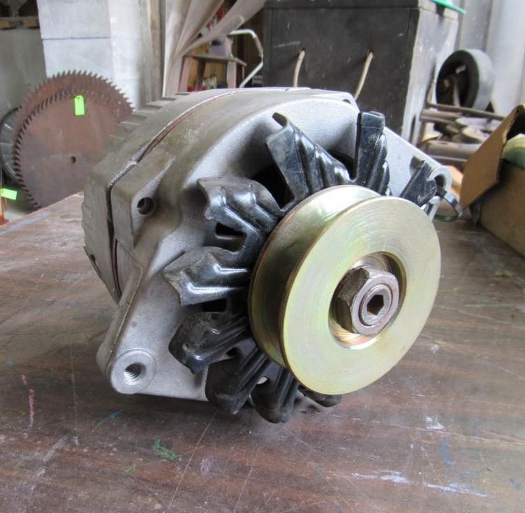 Silver alternator with a gold pulley, on a wooden surface.