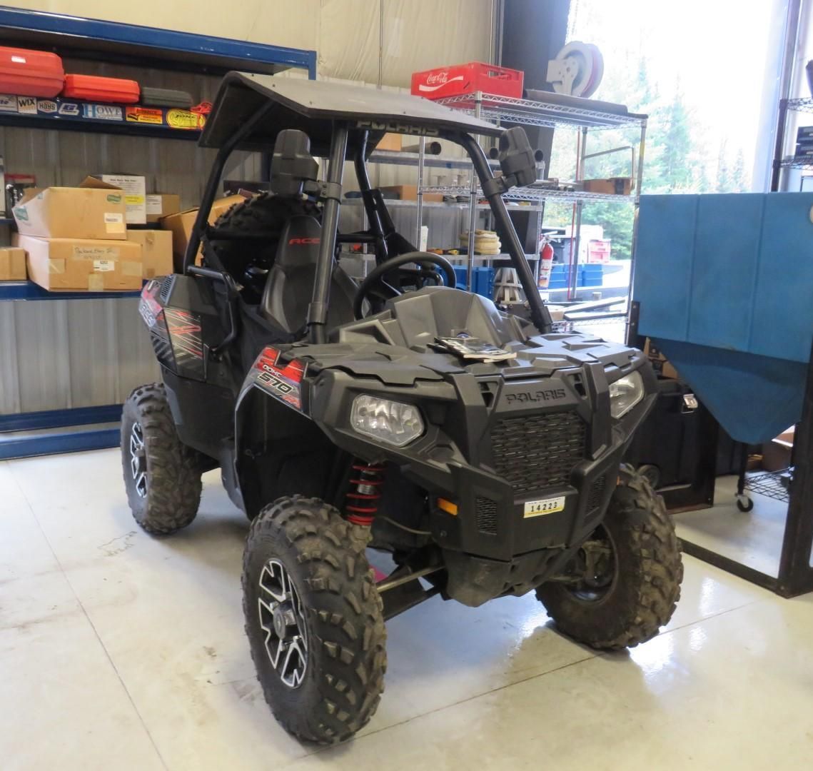 Black Polaris off-road vehicle with a roll cage, parked indoors.