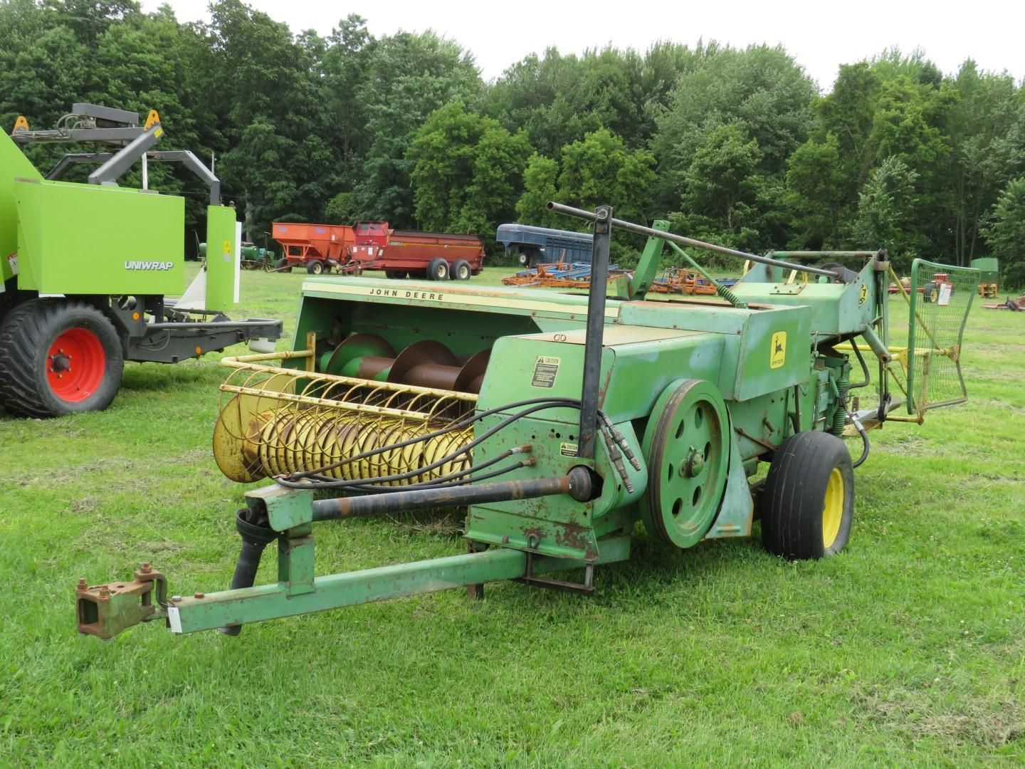 Green John Deere hay baler on a grassy field.